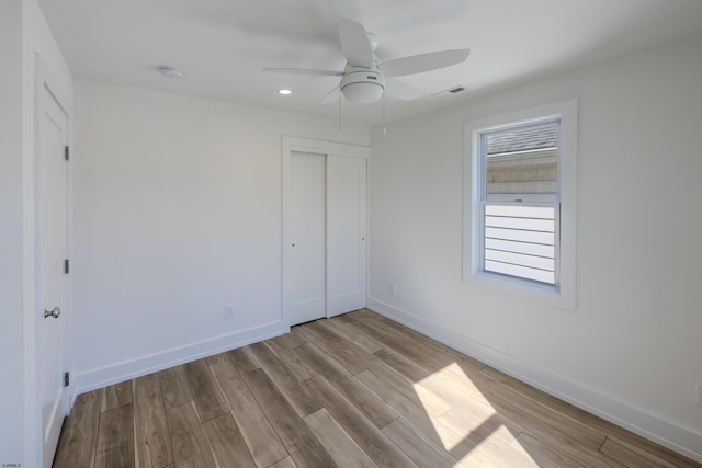 unfurnished bedroom featuring ceiling fan, a closet, and light wood-type flooring