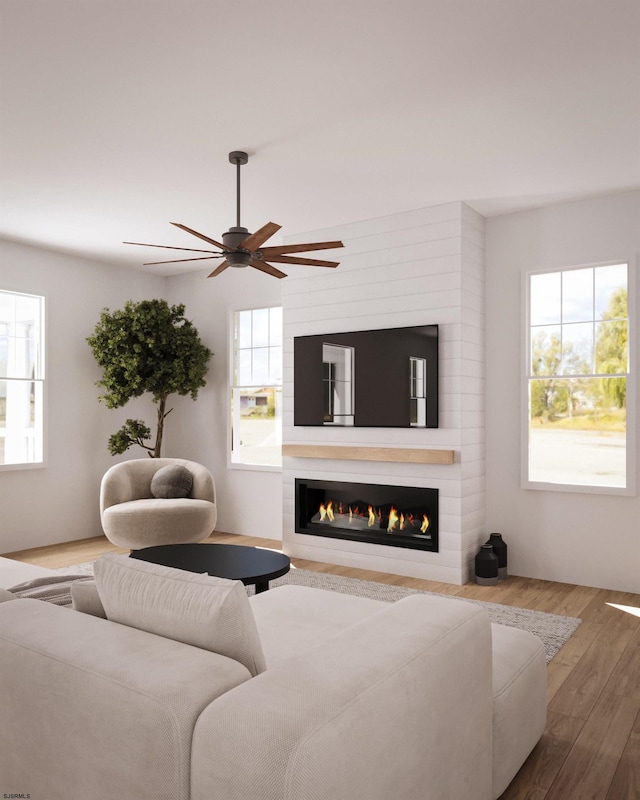 living room with ceiling fan, a large fireplace, and wood-type flooring