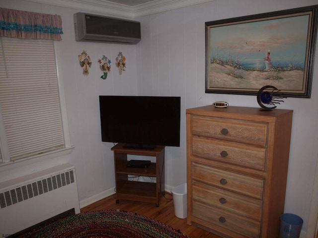 interior space featuring radiator heating unit, an AC wall unit, crown molding, and hardwood / wood-style floors