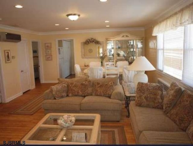 living room with a wall mounted air conditioner, wood-type flooring, and ornamental molding