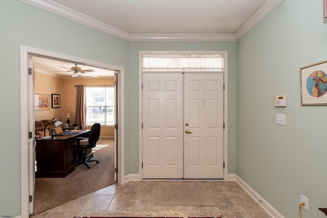 carpeted foyer with ceiling fan and ornamental molding