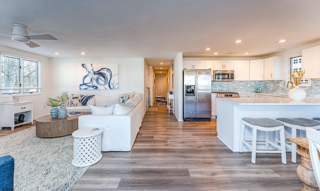 kitchen featuring ceiling fan, tasteful backsplash, appliances with stainless steel finishes, white cabinets, and light wood-type flooring