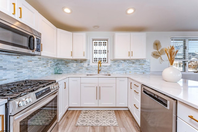 kitchen featuring white cabinets, appliances with stainless steel finishes, decorative backsplash, and sink