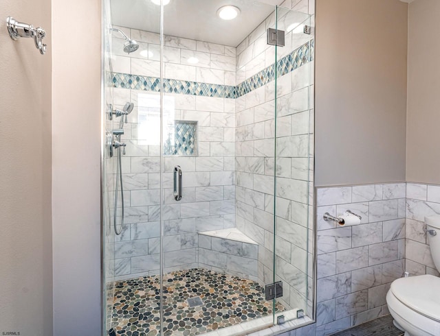 bathroom with an enclosed shower, toilet, and tile walls