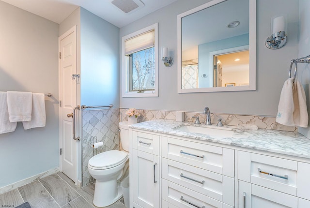 bathroom featuring vanity, toilet, and tile walls