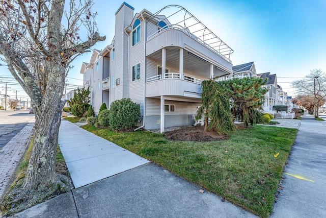 view of side of home featuring a lawn and a balcony