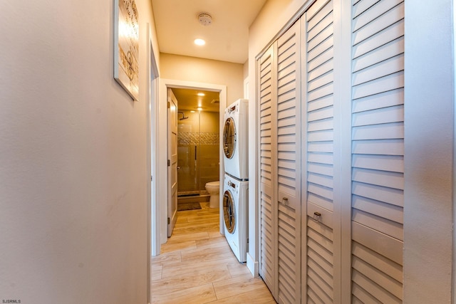 corridor with stacked washer / dryer and light hardwood / wood-style flooring