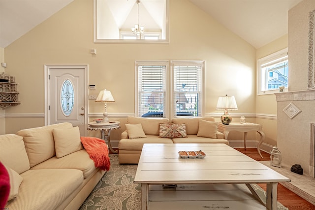 living room featuring wood-type flooring, high vaulted ceiling, and an inviting chandelier