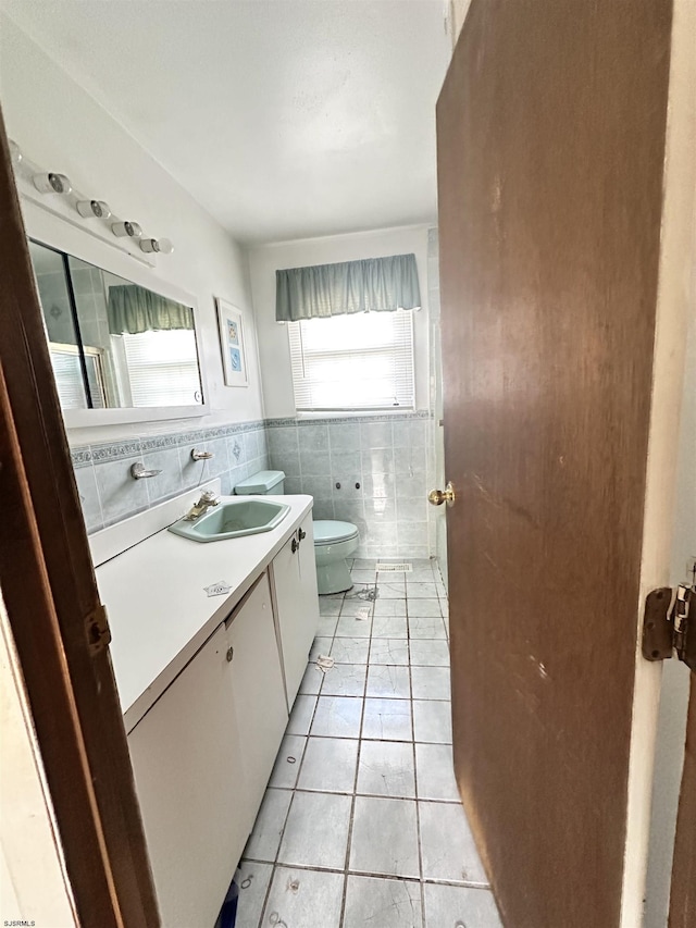 bathroom with tile patterned flooring, vanity, toilet, and tile walls