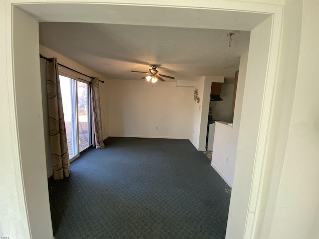 unfurnished room with ceiling fan, dark carpet, and a textured ceiling