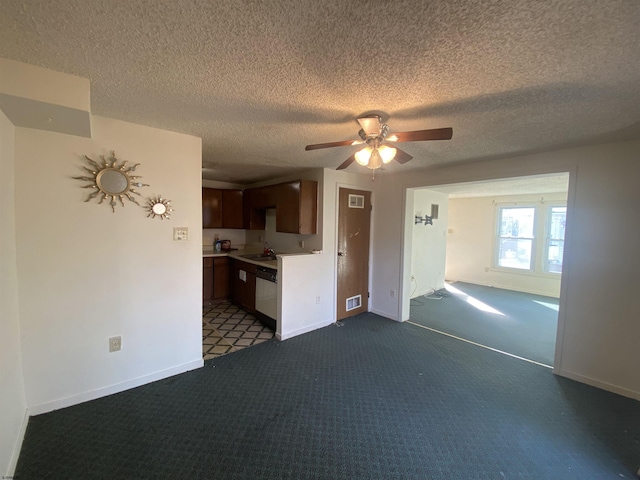 unfurnished living room featuring ceiling fan, sink, a textured ceiling, and dark colored carpet