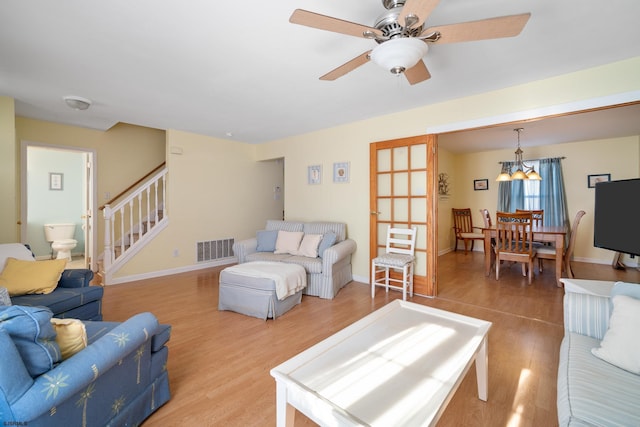 living room with wood-type flooring and ceiling fan with notable chandelier