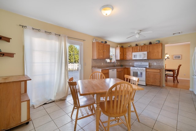 tiled dining area with ceiling fan and sink