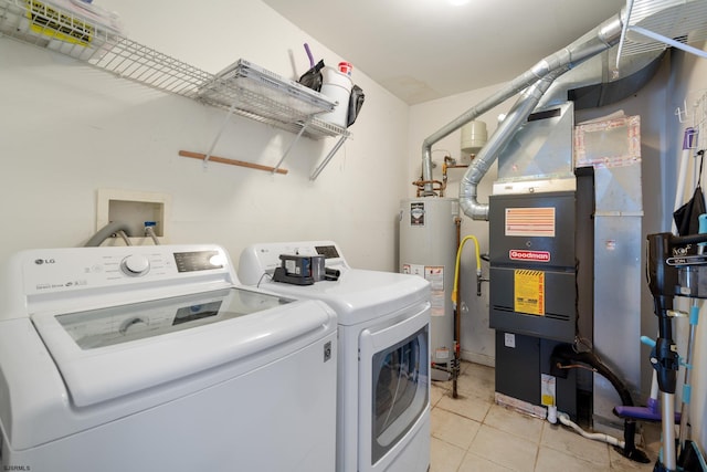 laundry area with heating unit, gas water heater, light tile patterned floors, and washing machine and clothes dryer