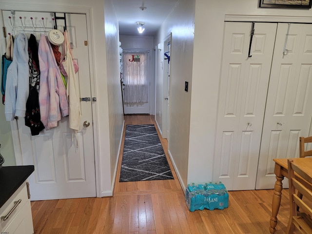 corridor featuring light wood-style flooring and baseboards