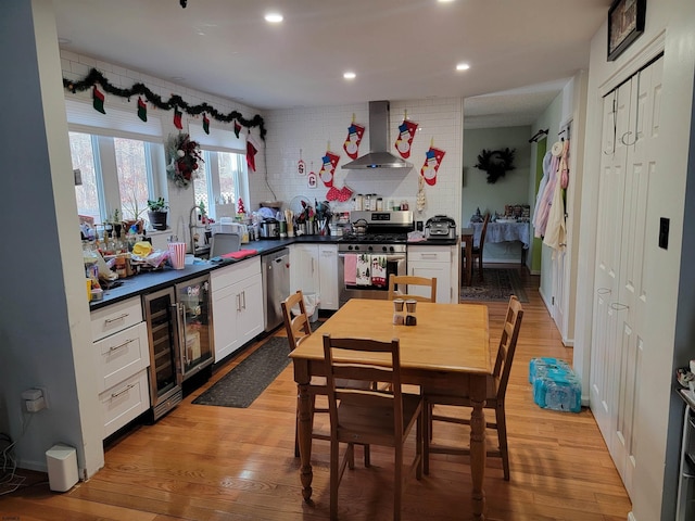 kitchen with tasteful backsplash, wall chimney exhaust hood, stainless steel appliances, light hardwood / wood-style floors, and white cabinetry