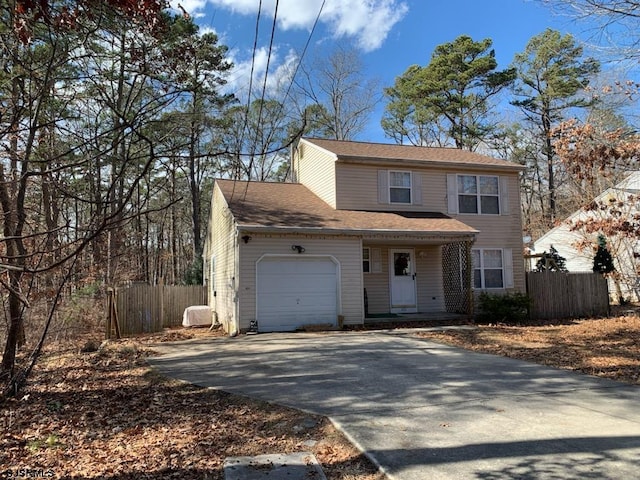 traditional-style house with driveway, an attached garage, and fence