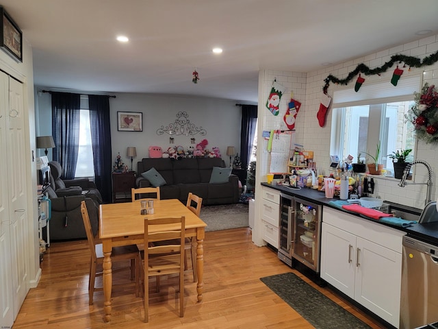 kitchen with light wood finished floors, dishwasher, wine cooler, open floor plan, and a sink