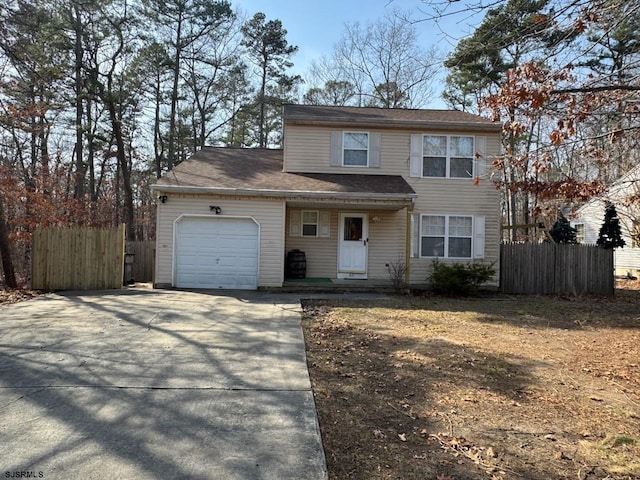 traditional home with an attached garage, fence, and driveway