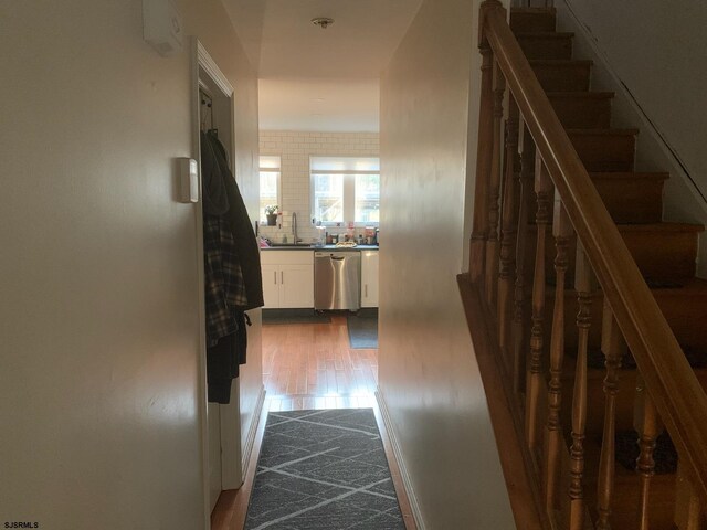 corridor with stairway, dark wood-style floors, and a sink