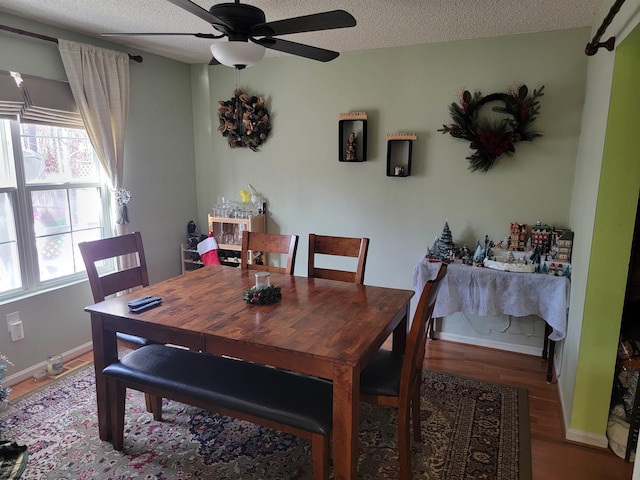 dining space with baseboards, a ceiling fan, a textured ceiling, and wood finished floors