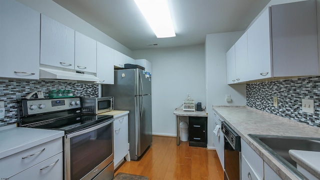 kitchen with sink, stainless steel appliances, light hardwood / wood-style flooring, decorative backsplash, and white cabinets