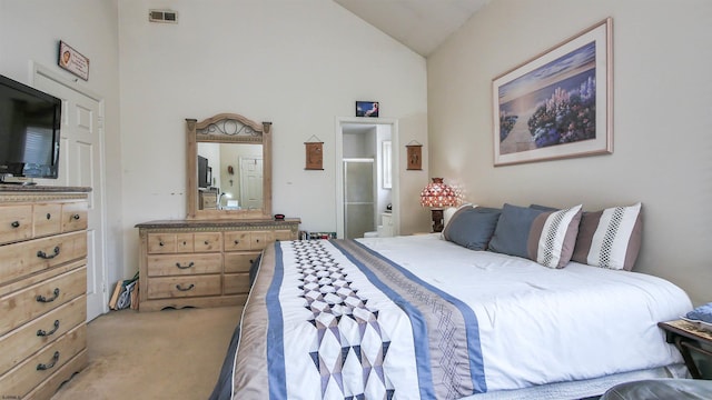 carpeted bedroom with ensuite bathroom and vaulted ceiling