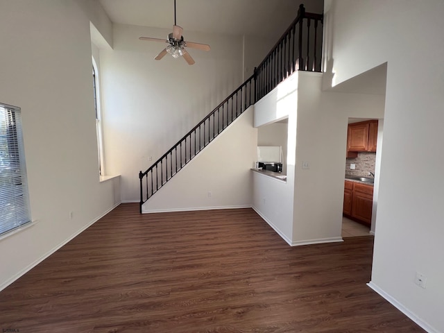 unfurnished living room featuring dark hardwood / wood-style floors, ceiling fan, and a high ceiling