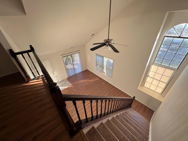 stairway featuring a wealth of natural light, ceiling fan, wood-type flooring, and high vaulted ceiling