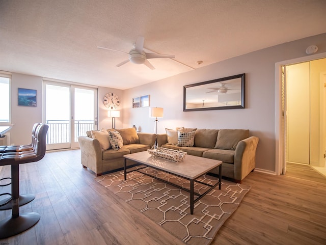 living room featuring floor to ceiling windows, wood-type flooring, a textured ceiling, and ceiling fan