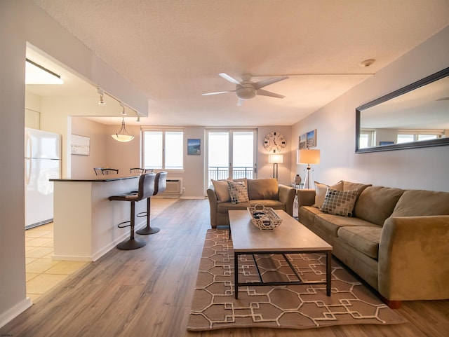 living room with wood-type flooring, rail lighting, and ceiling fan