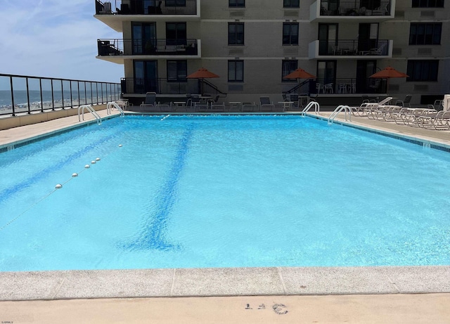 view of swimming pool with a patio area and a water view