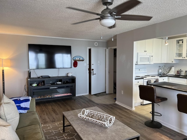 living room featuring hardwood / wood-style floors, ceiling fan, sink, and a textured ceiling