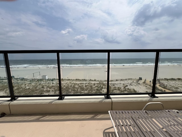 balcony featuring a water view and a beach view