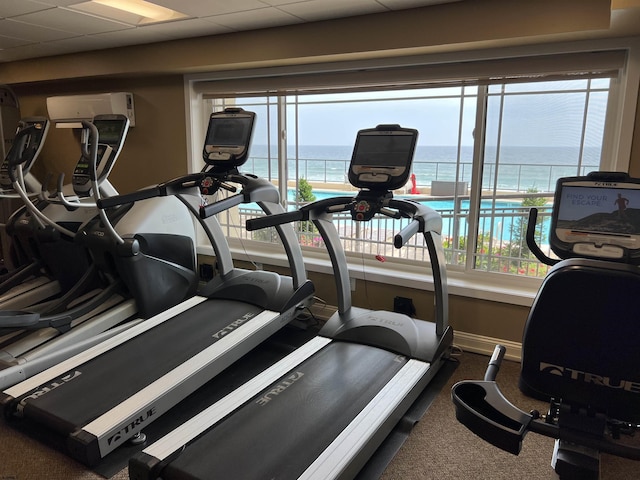 workout area featuring a paneled ceiling and a water view