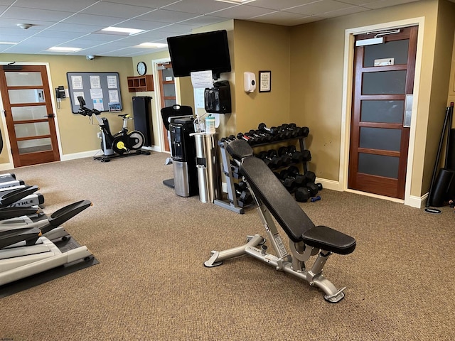 exercise room featuring carpet flooring and a paneled ceiling