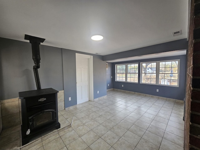 unfurnished living room featuring light tile patterned flooring and a wood stove