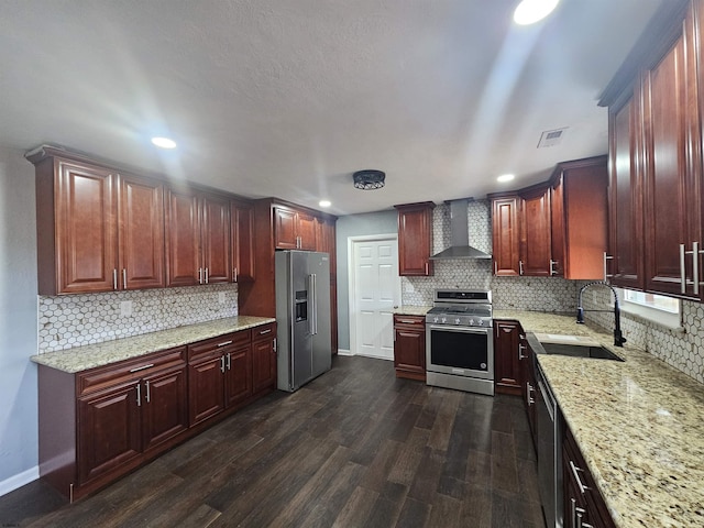 kitchen with sink, stainless steel appliances, light stone countertops, dark wood-type flooring, and wall chimney range hood