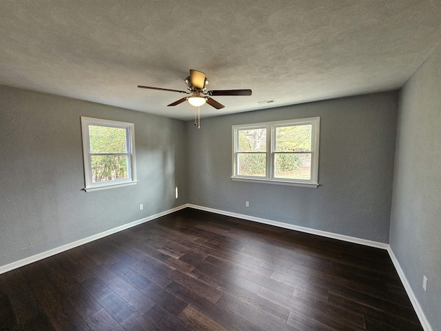 empty room featuring dark hardwood / wood-style floors, a wealth of natural light, and ceiling fan