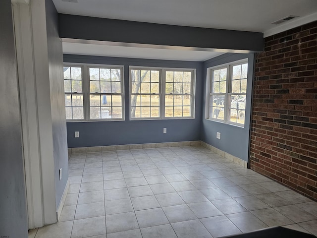 tiled spare room featuring plenty of natural light and brick wall