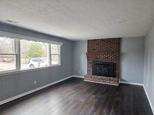 unfurnished living room featuring a textured ceiling, a wood stove, and dark wood-type flooring