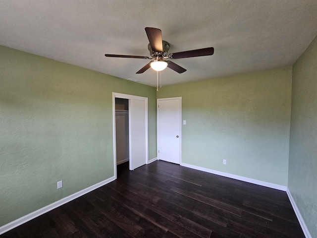 unfurnished bedroom featuring dark wood-type flooring, ceiling fan, and a closet