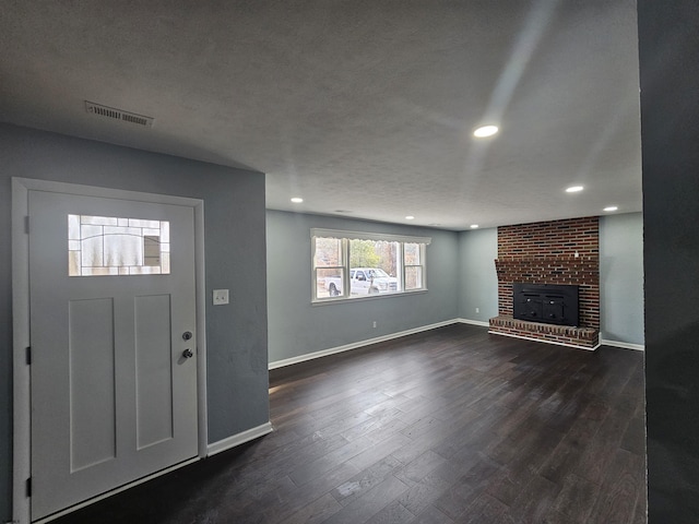 entrance foyer with a fireplace, dark wood-type flooring, and a textured ceiling