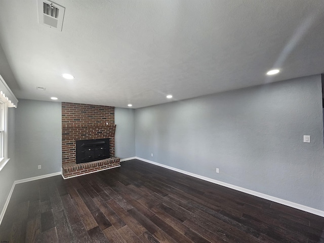 unfurnished living room with a brick fireplace and dark hardwood / wood-style floors