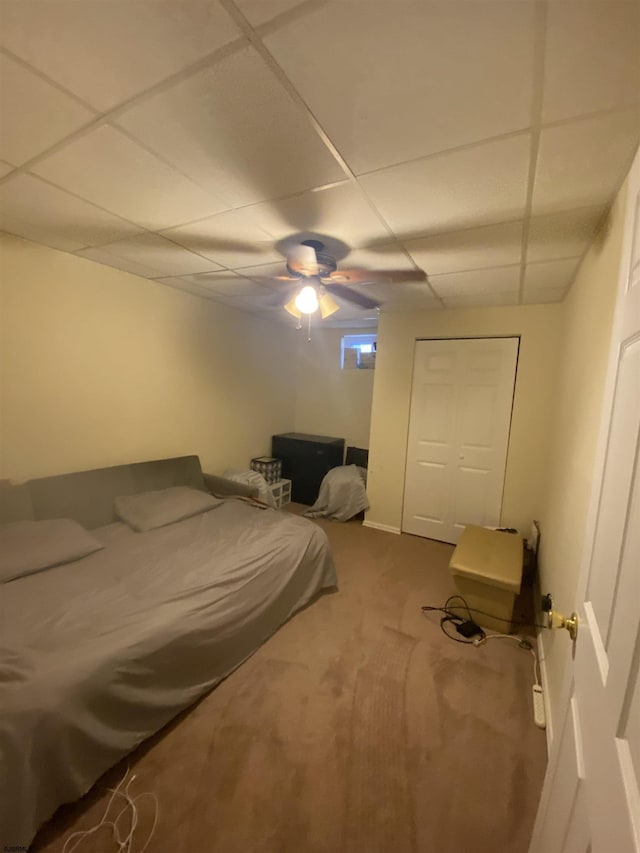 carpeted bedroom with a paneled ceiling and ceiling fan