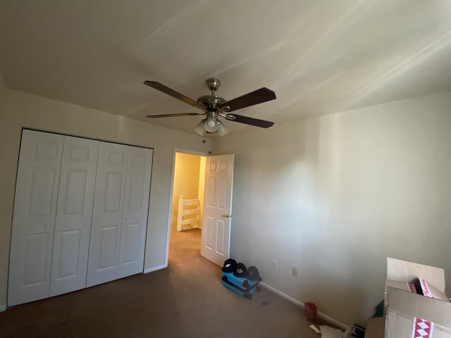 unfurnished bedroom featuring ceiling fan, a closet, and dark carpet