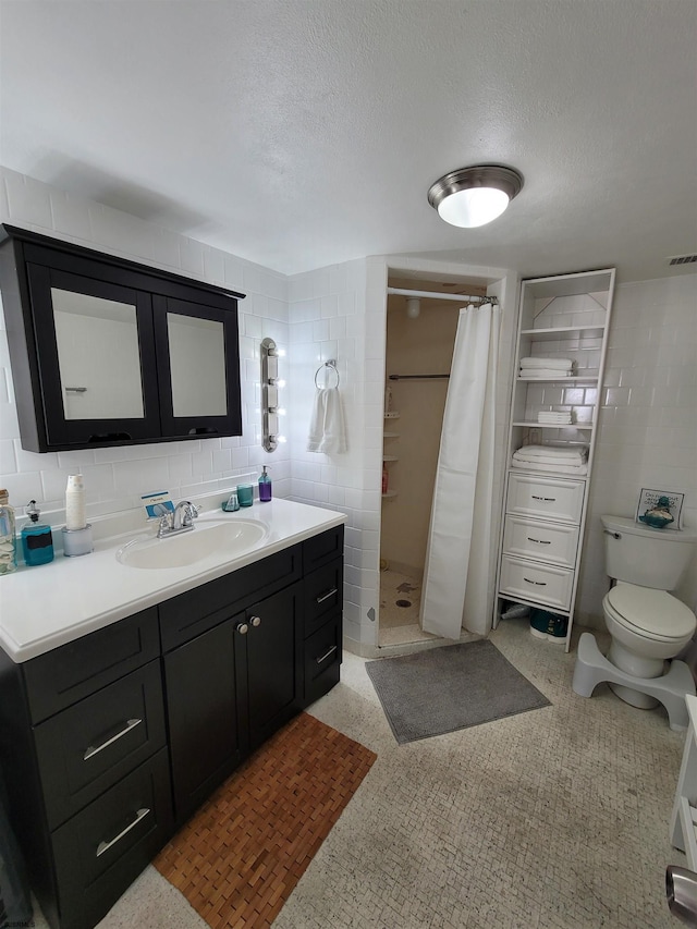 bathroom featuring a shower with shower curtain, vanity, a textured ceiling, tile walls, and toilet