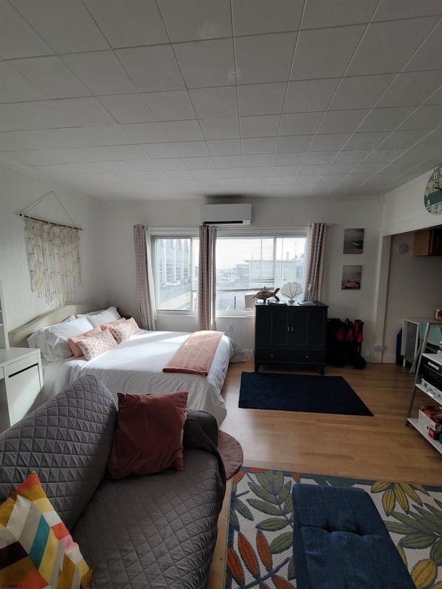 bedroom with a wall unit AC, multiple windows, and hardwood / wood-style flooring