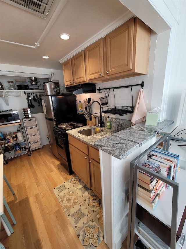 kitchen featuring backsplash, black gas stove, sink, light hardwood / wood-style flooring, and light stone counters