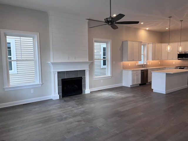 kitchen with pendant lighting, backsplash, white cabinets, sink, and dishwashing machine